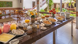 A buffet setup with various food items, drinks, and a decorative centerpiece. -  Quinta do Sol Lite Hotel (Porto Seguro)