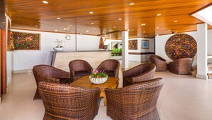 A spacious indoor area with wicker furniture, a wooden ceiling, and a reception desk. -  Quinta do Sol Lite Hotel (Porto Seguro)