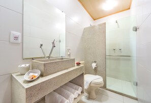 Une salle de bain moderne avec un comptoir en granit, une cabine de douche en verre et des toilettes.