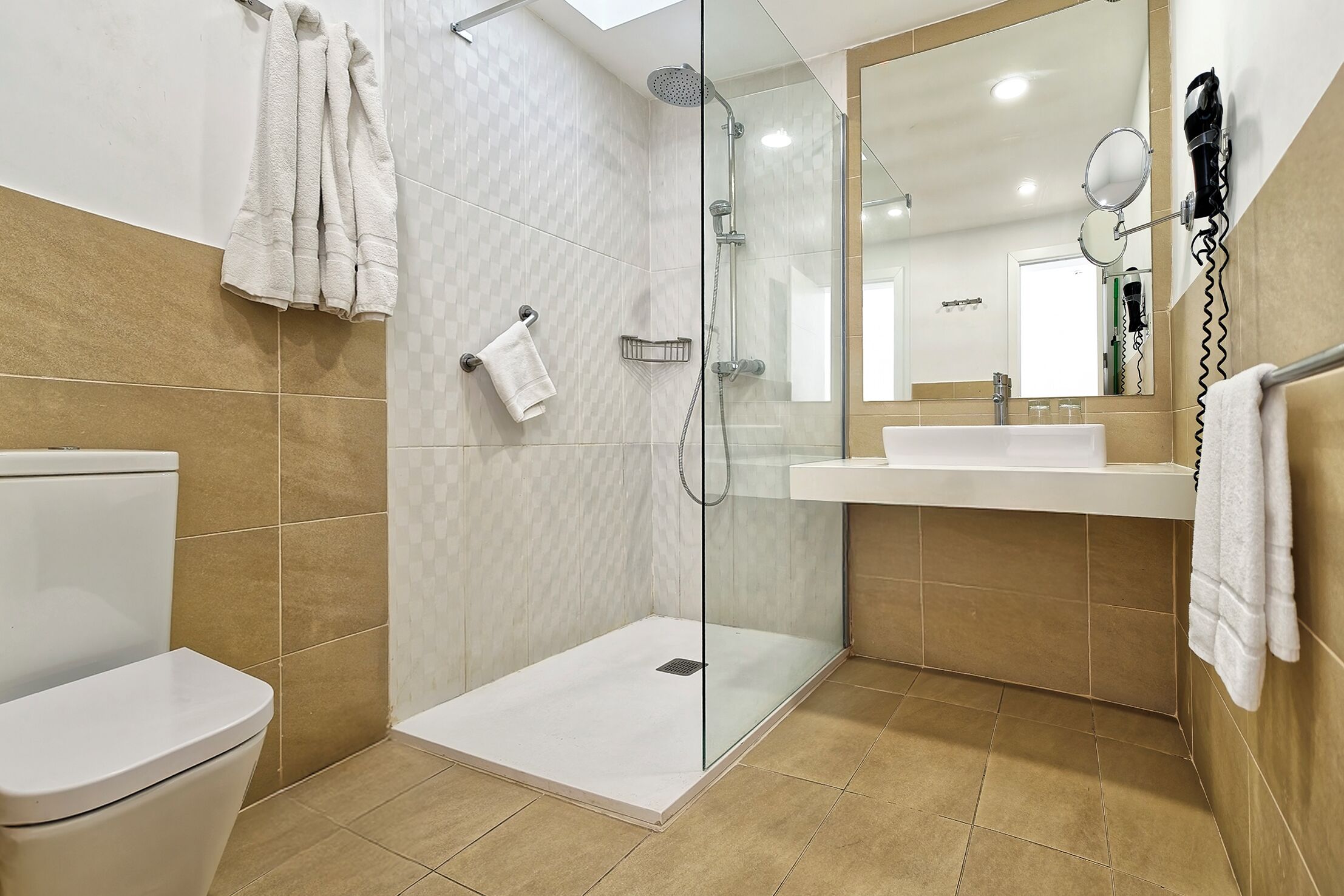 Een moderne badkamer met een glazen douchecabine, een wit toilet en een wastafel met spiegel.