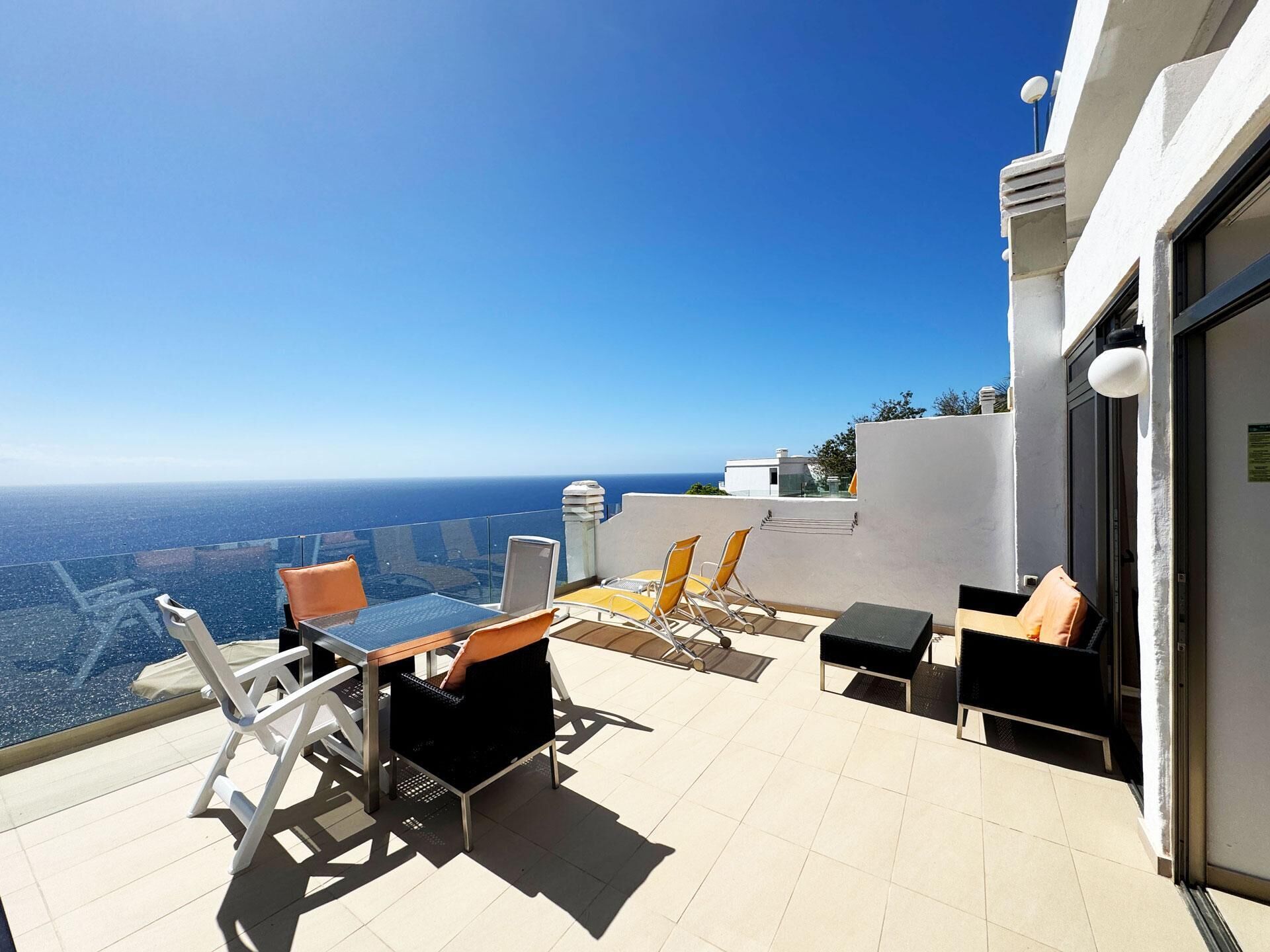 Eine Dachterrasse mit freiem Blick auf den Ozean, möbliert mit Stühlen und einem Tisch.