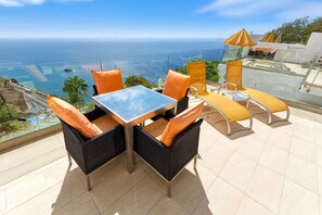 A terrace with a table and chairs, overlooking a coastal view. - Servatur Altamar (Mogan)