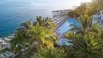 Un resort con piscina, palmeras y vistas al mar.