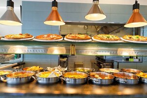 Un bufé con distintos platos y una presentación de pizza.