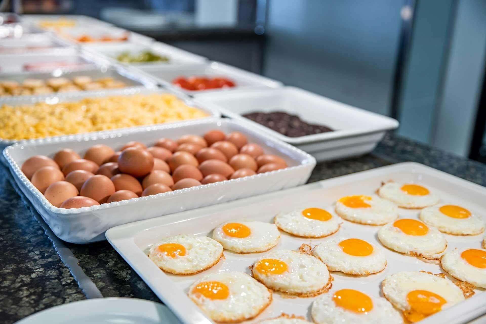 Een buffet met diverse gerechten, waaronder eieren, kaas en andere vleeswaren.