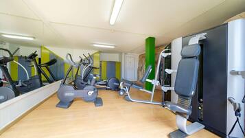 Een sportschool met cardioapparatuur, gewichten en een spiegelwand.