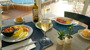 Una mesa servida con una botella de vino, una copa de vino blanco y platos de comida que incluyen mariscos, verduras y tostadas.