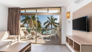 A modern hotel room with a balcony, a sofa, a TV, and a pool view. - Servatur Edén & Buganvillas (Mogan)