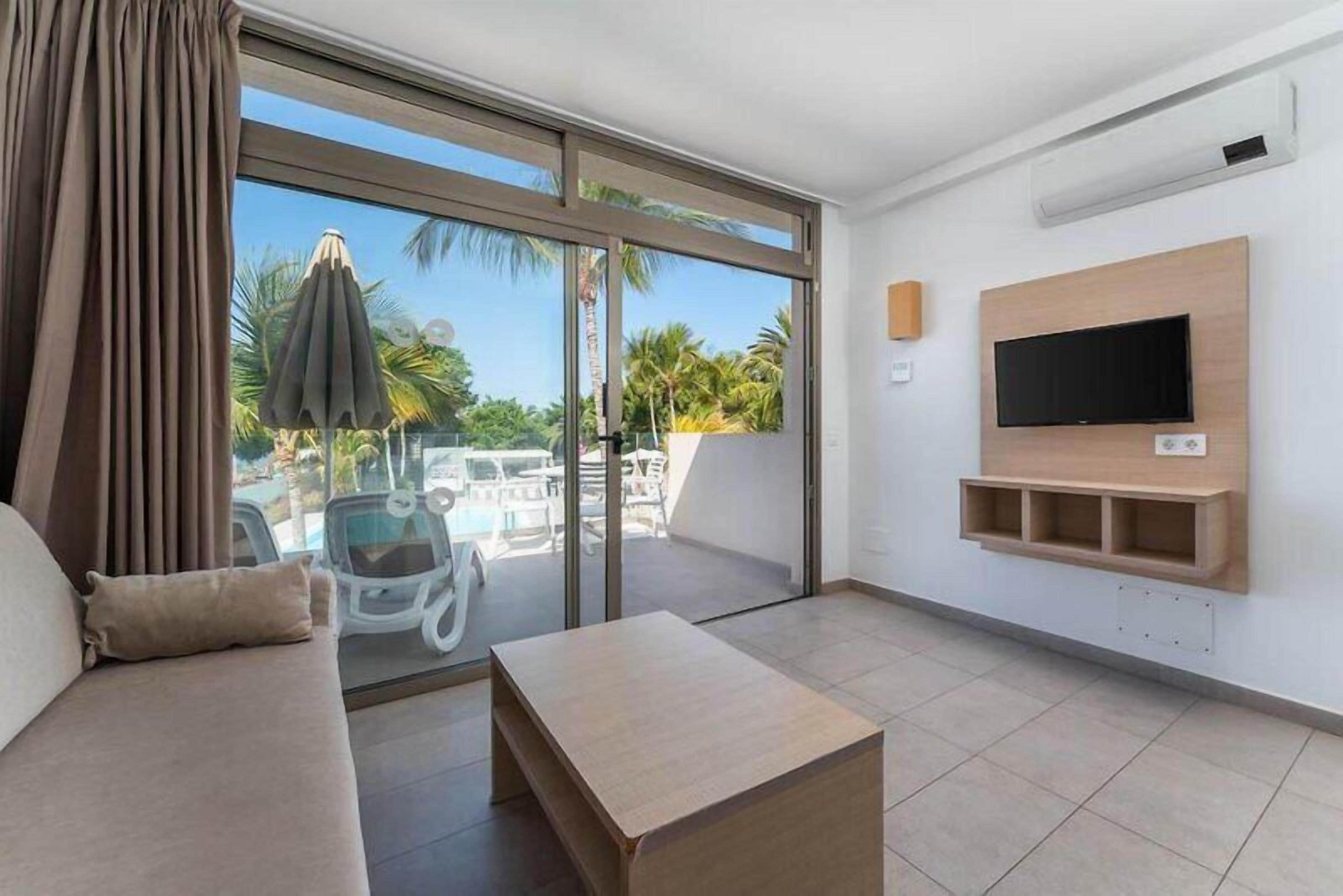 Ein modernes Wohnzimmer mit einer Couch, einem Couchtisch und einem an der Wand montierten Fernseher.