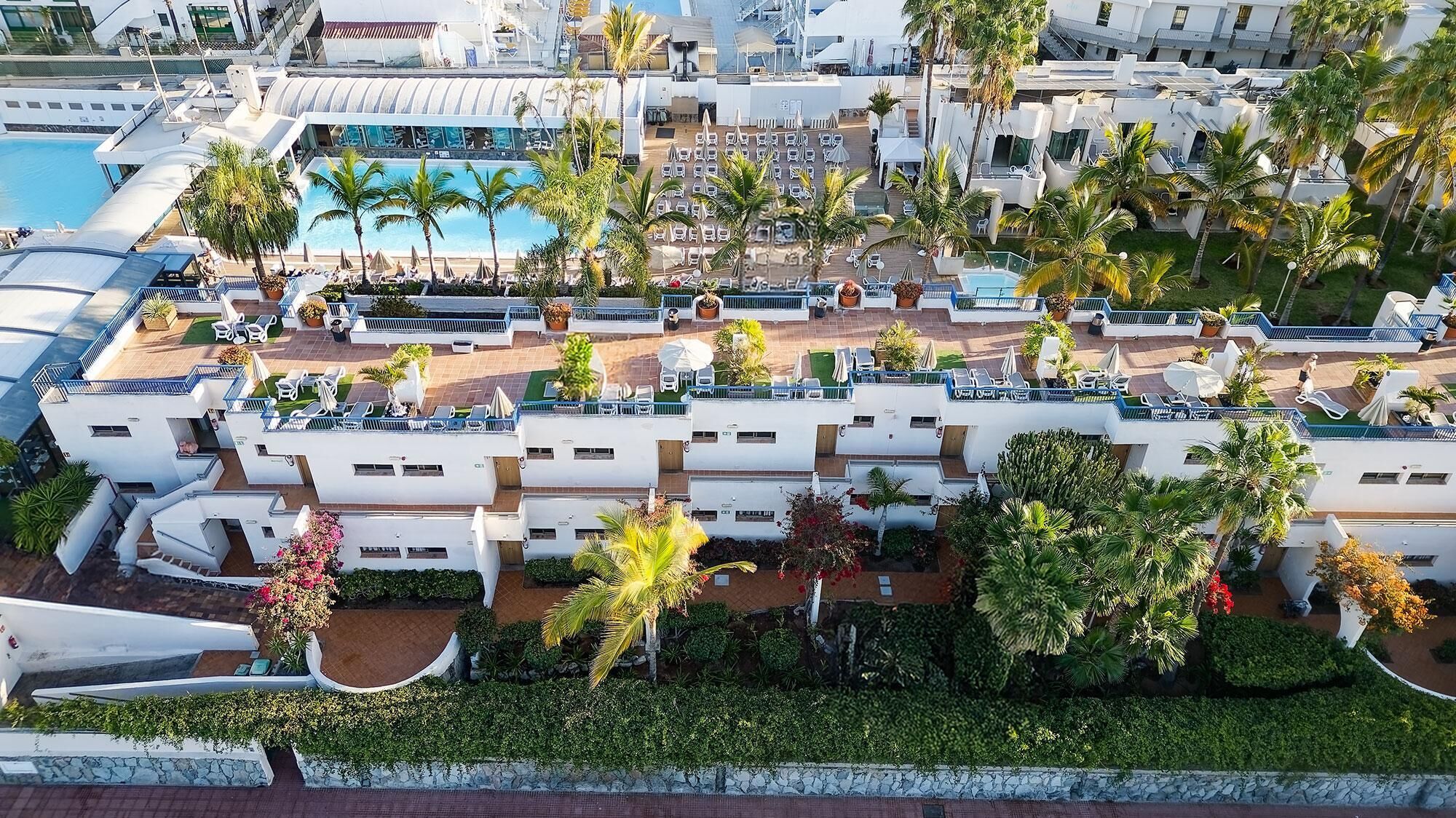 A resort with multiple swimming pools, palm trees, and outdoor seating areas.