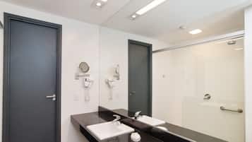 Ein modernes Badezimmer mit zwei Waschbecken, einem großen Spiegel und einer Duschkabine.