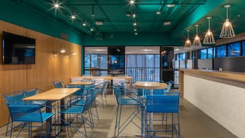Un restaurante moderno con sillas de metal azul, mesas de madera e iluminación colgante.