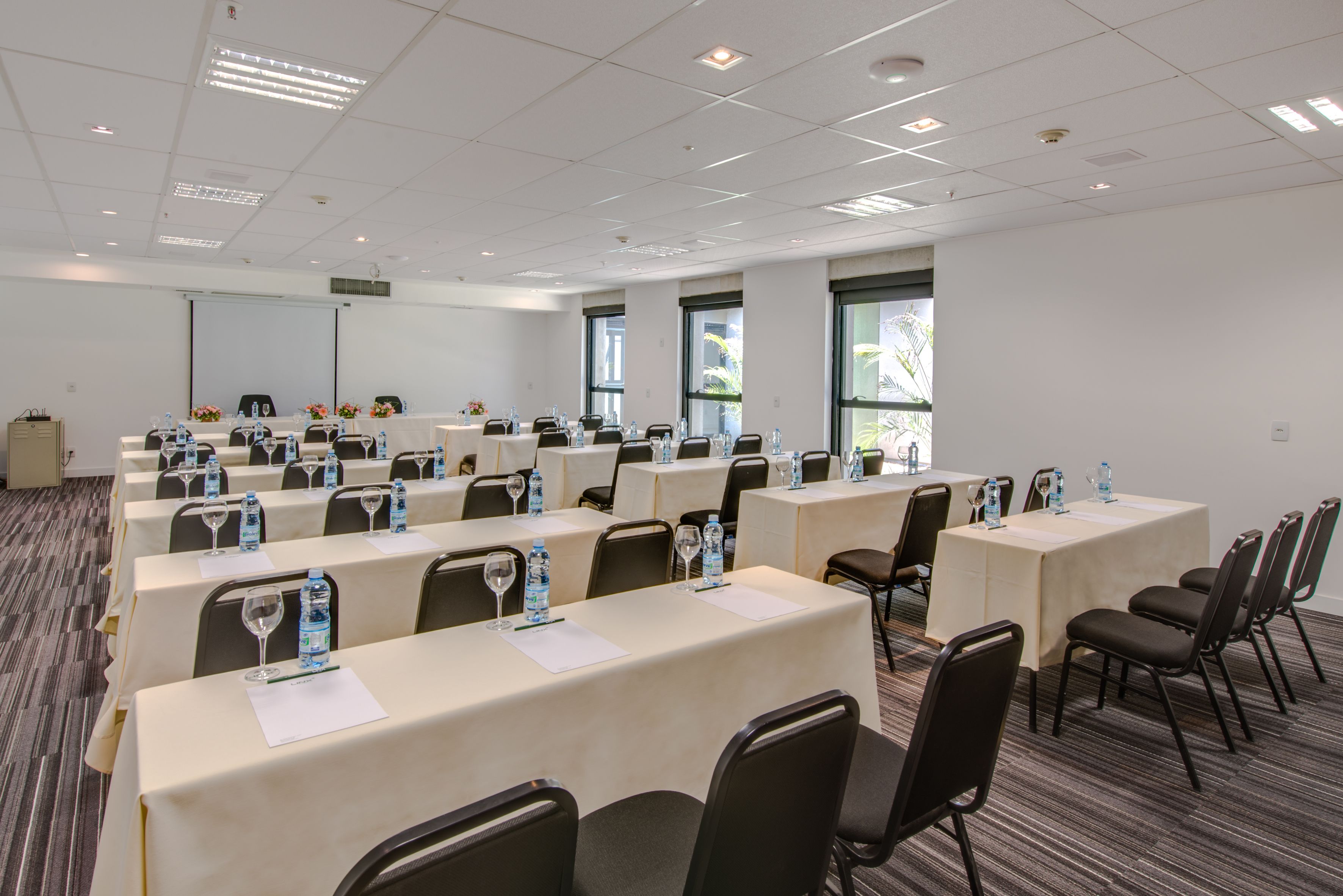 Une salle de conférence équipée de plusieurs tables, de chaises et de bouteilles d’eau.