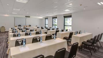 Une salle de conférence équipée de plusieurs tables, de chaises et de bouteilles d’eau.