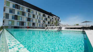 Un hôtel doté d’une piscine, d’un espace extérieur aménagé et surplombant un ciel d’un bleu éclatant.