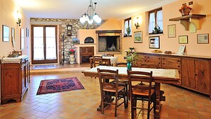 A spacious kitchen with a dining area, stone wall, wooden cabinets, and a fireplace.