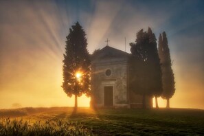 A small building with a central door and a cross on top, surrounded by trees. - Agriturismo La Buca di Bellugi (San Quirico d'Orcia)