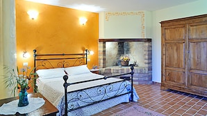 A bedroom with a bed, a fireplace, and a wooden wardrobe.