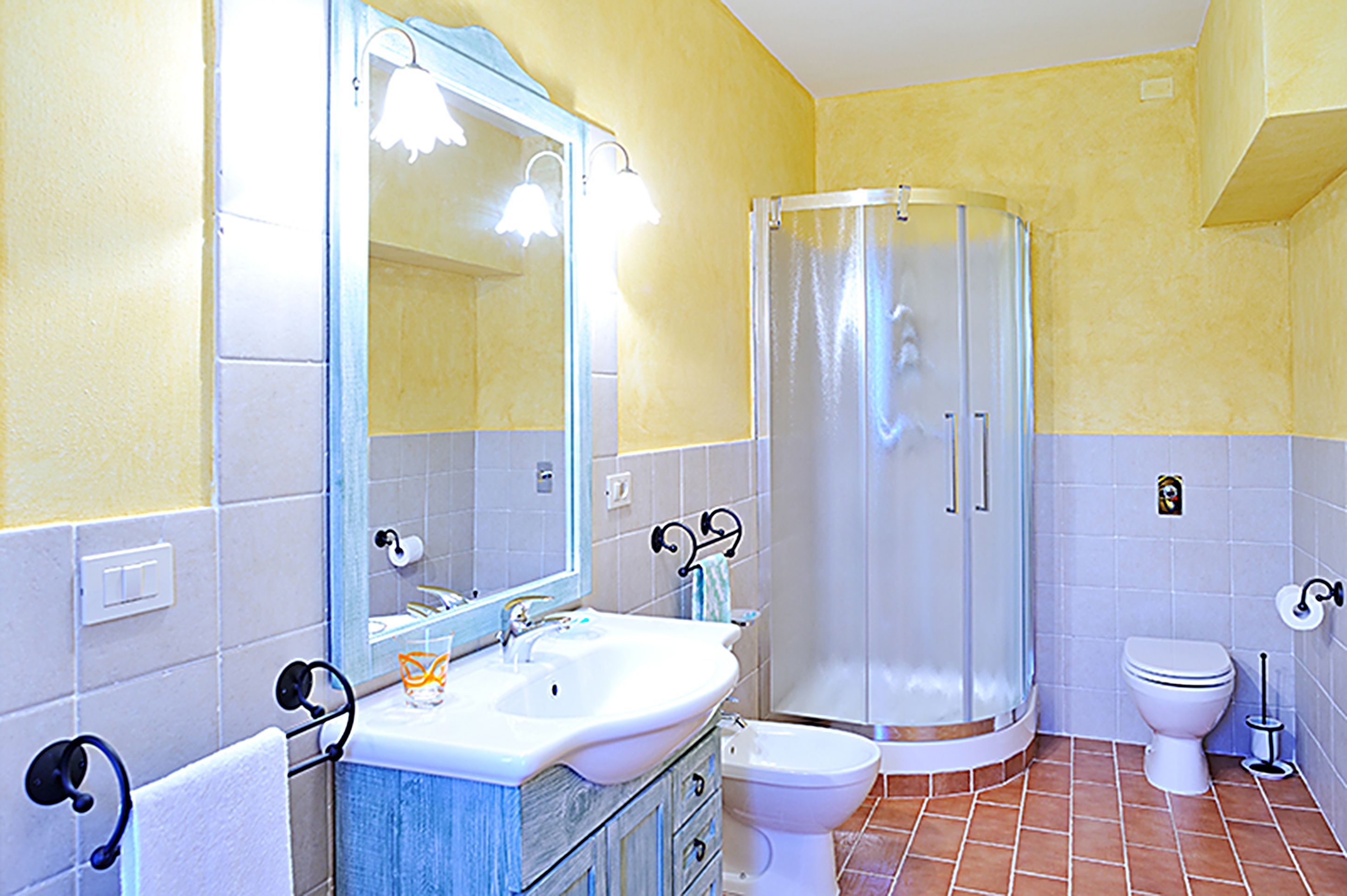A bathroom with a sink, mirror, shower, and toilet.
