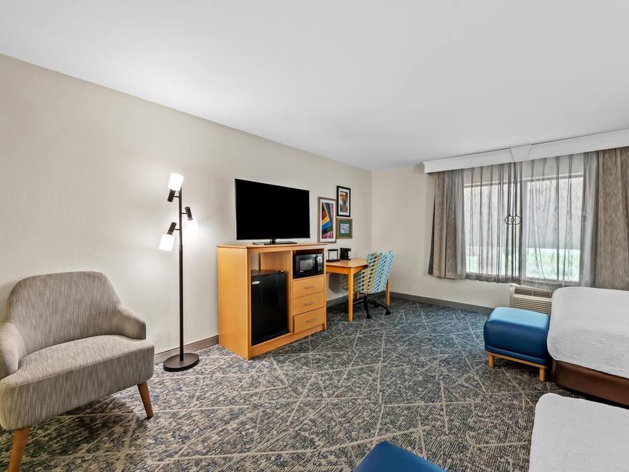 Una habitación de hotel con sofá, escritorio, computadora, televisor y cama.