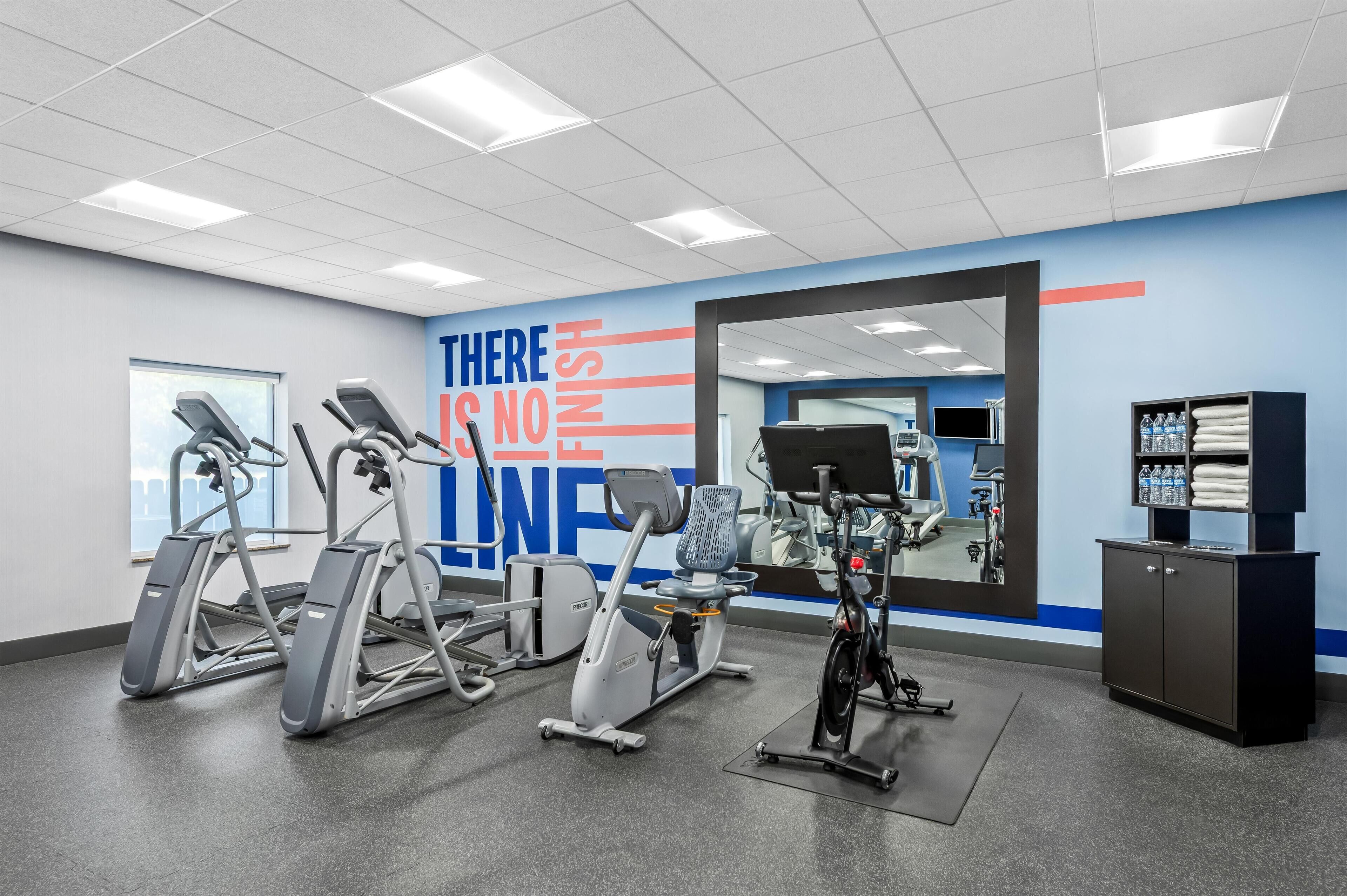 A gym with various exercise equipment, a motivational wall, and a water station.