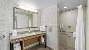 A modern bathroom with a large mirror, a sink, a shower, and a towel rack.