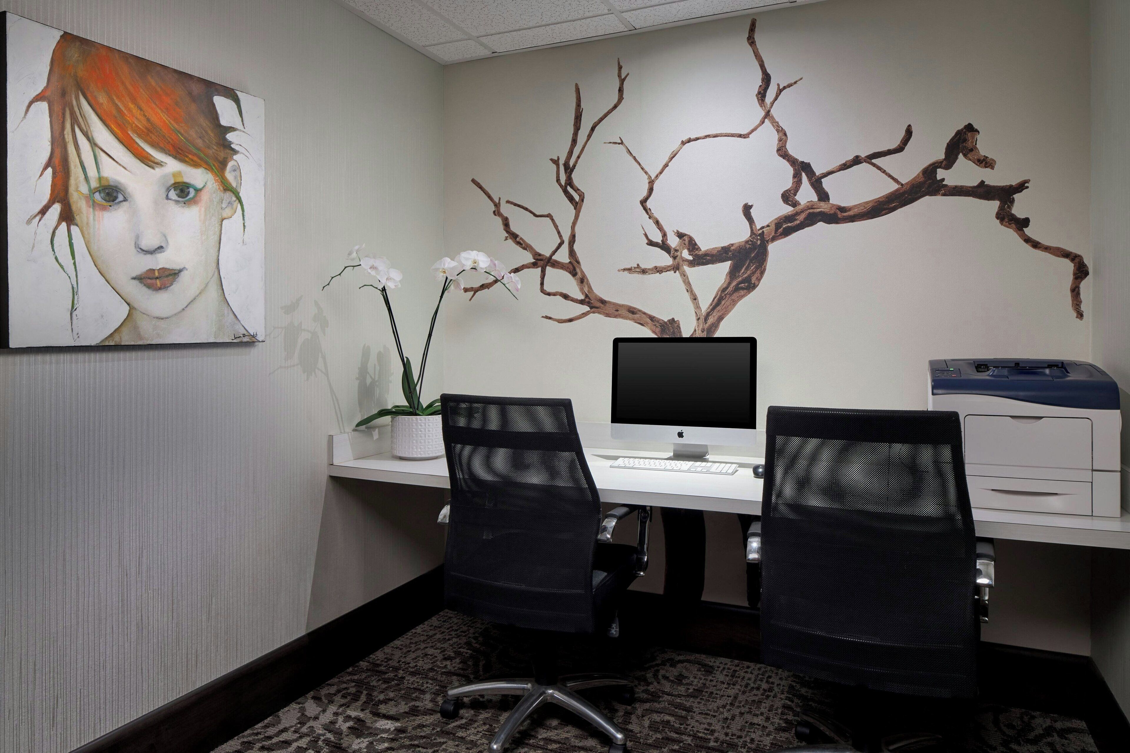 Un bureau avec deux chaises, un bureau, un ordinateur et une plante fixée au mur.