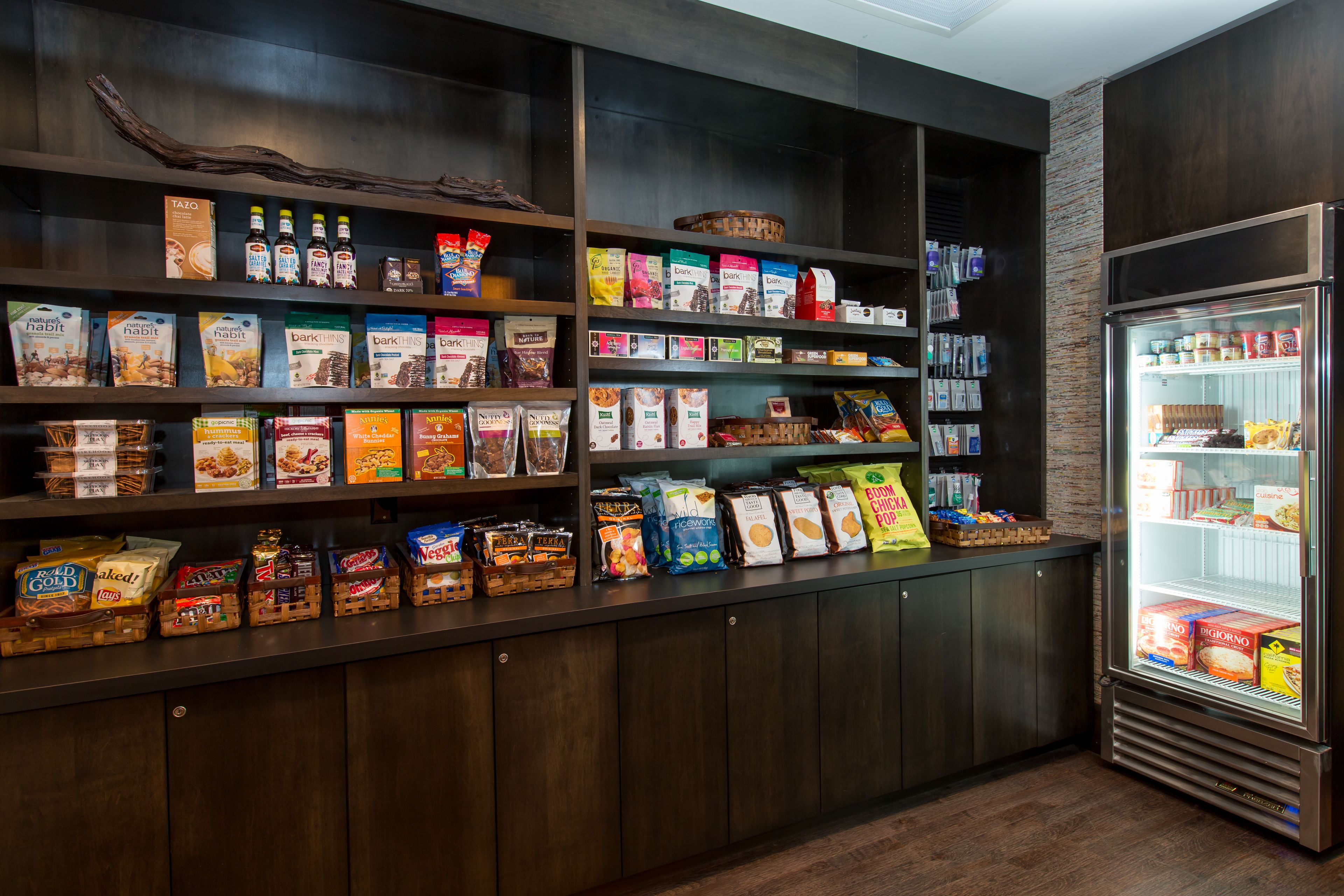 Un bar servant des collations, avec des étagères remplies de divers produits emballés, des boissons et un réfrigérateur-vitrine.