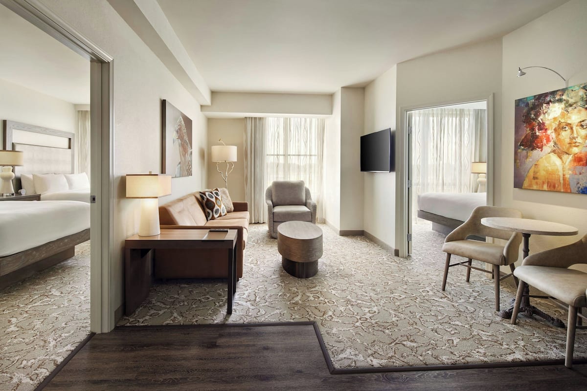 A hotel room with a bed, a sofa, a chair, a small table, and a TV.