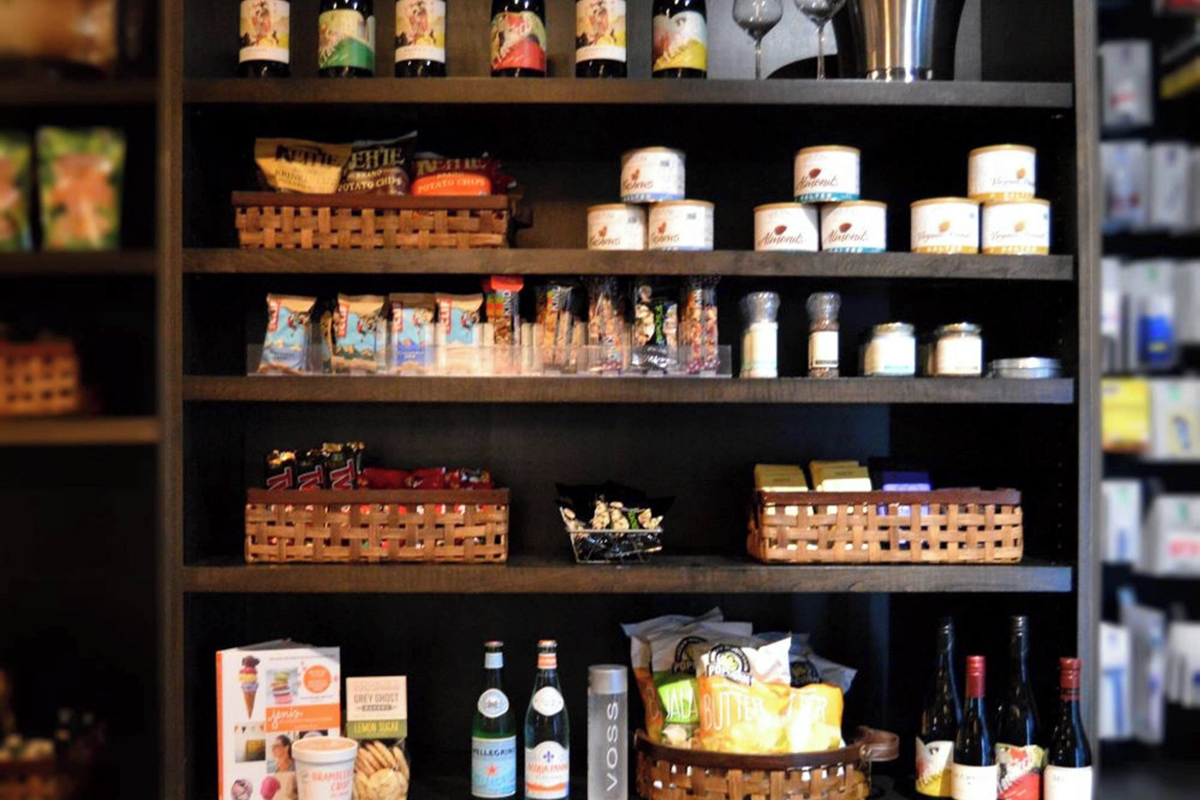 Une étagère remplie de divers produits alimentaires, notamment des bocaux, des boîtes et des bouteilles.
