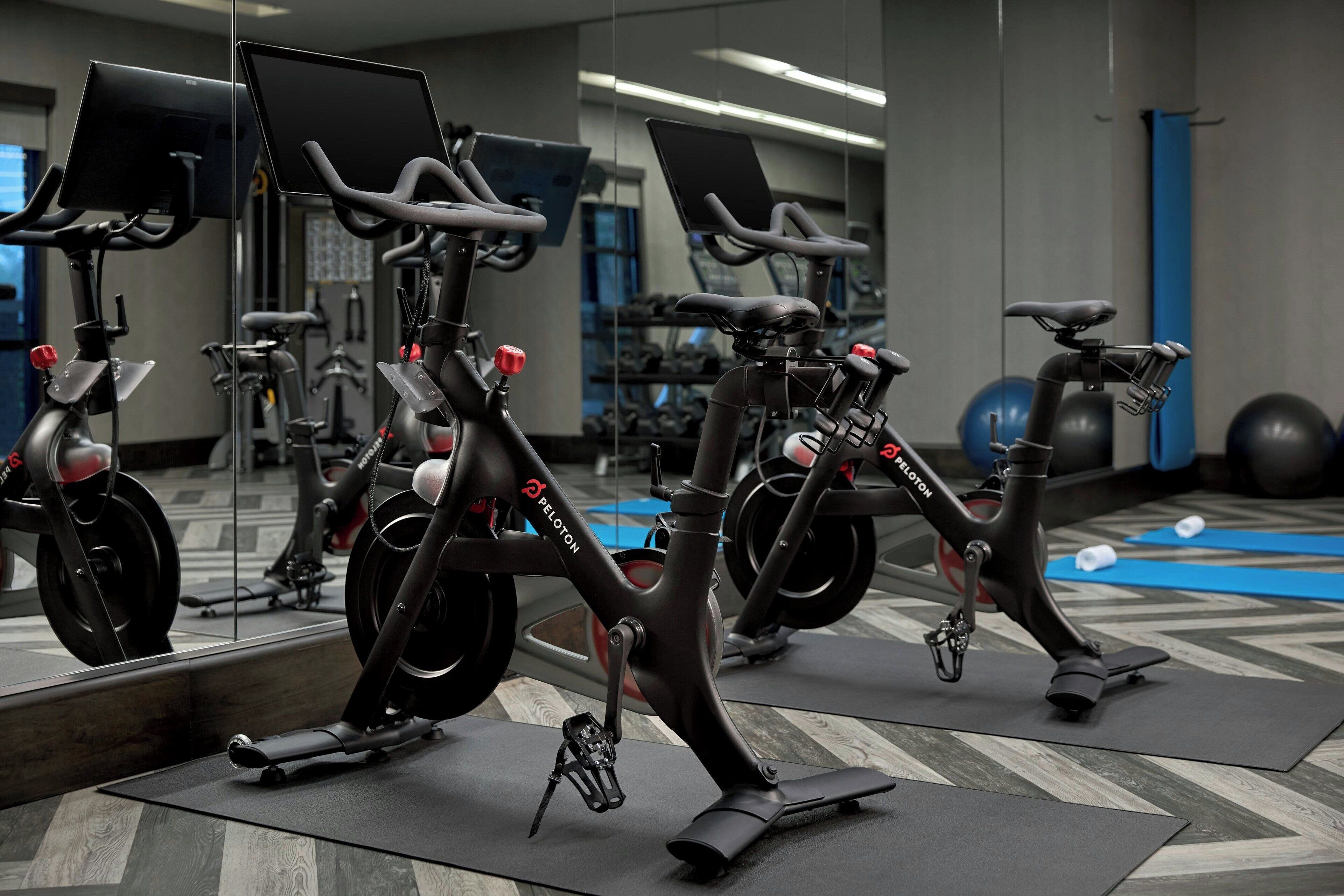 Et træningscenter med motionscykler, træningsbolde og et spejl der viser træningsudstyret.