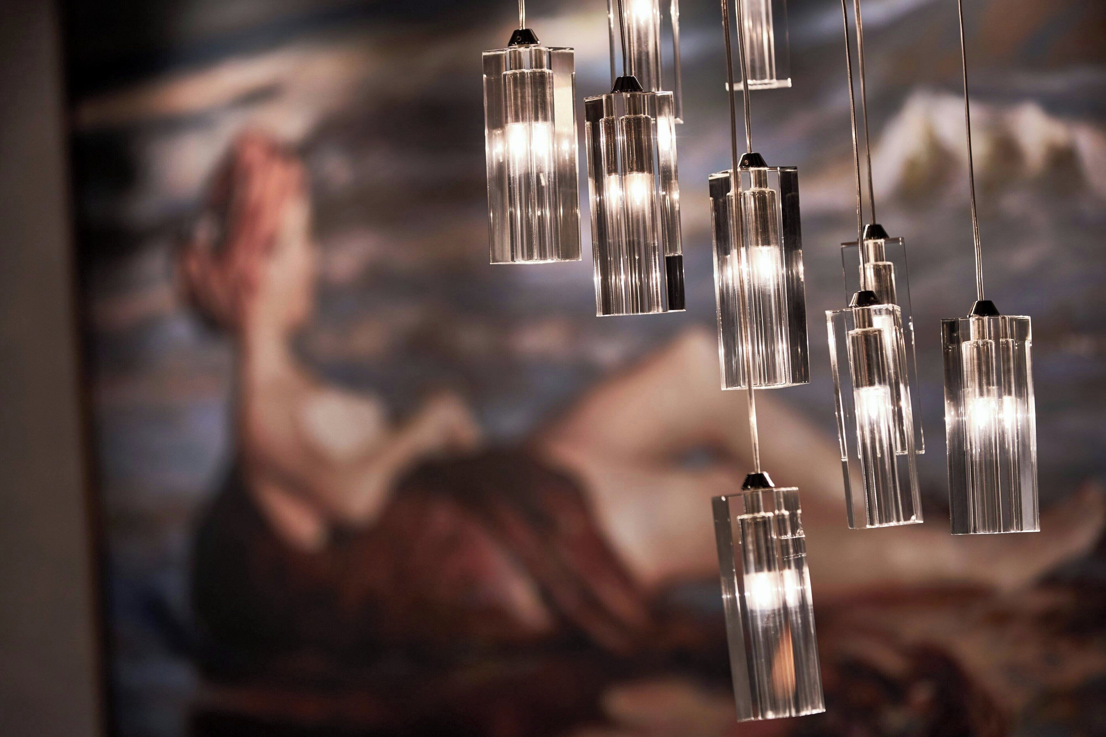 Une série de suspensions lumineuses dont les abat-jour sont transparents et réfléchissants.