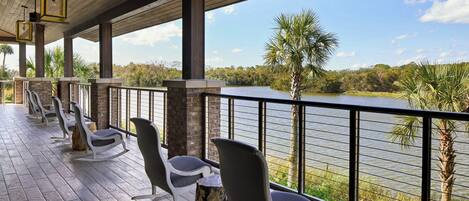 A covered outdoor seating area with chairs and a view of a lake.