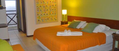 A hotel room with a large bed, a nightstand, a lamp, and a colorful wall decoration.