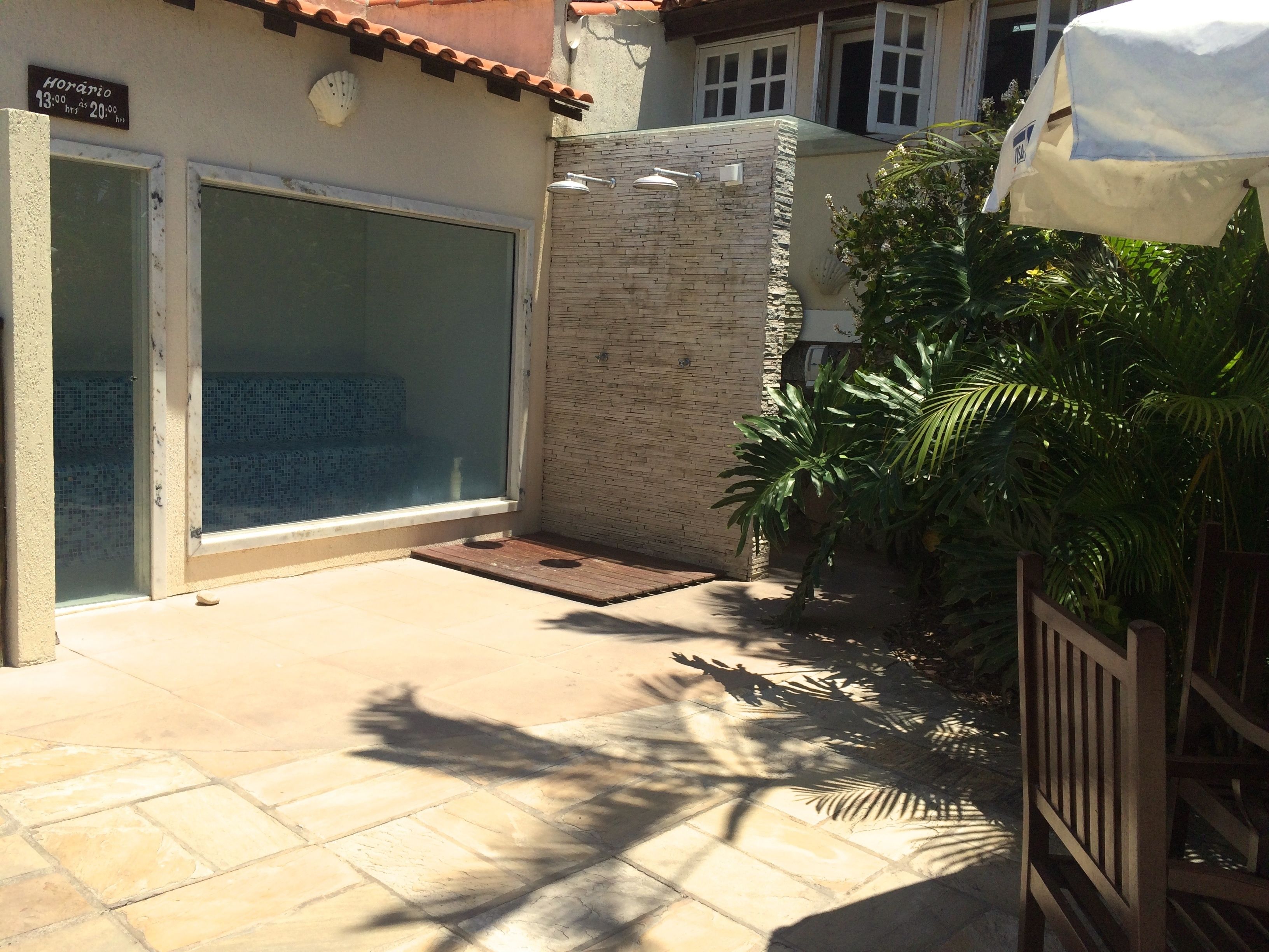 A courtyard with a tiled floor, a glass door, and a stone wall.