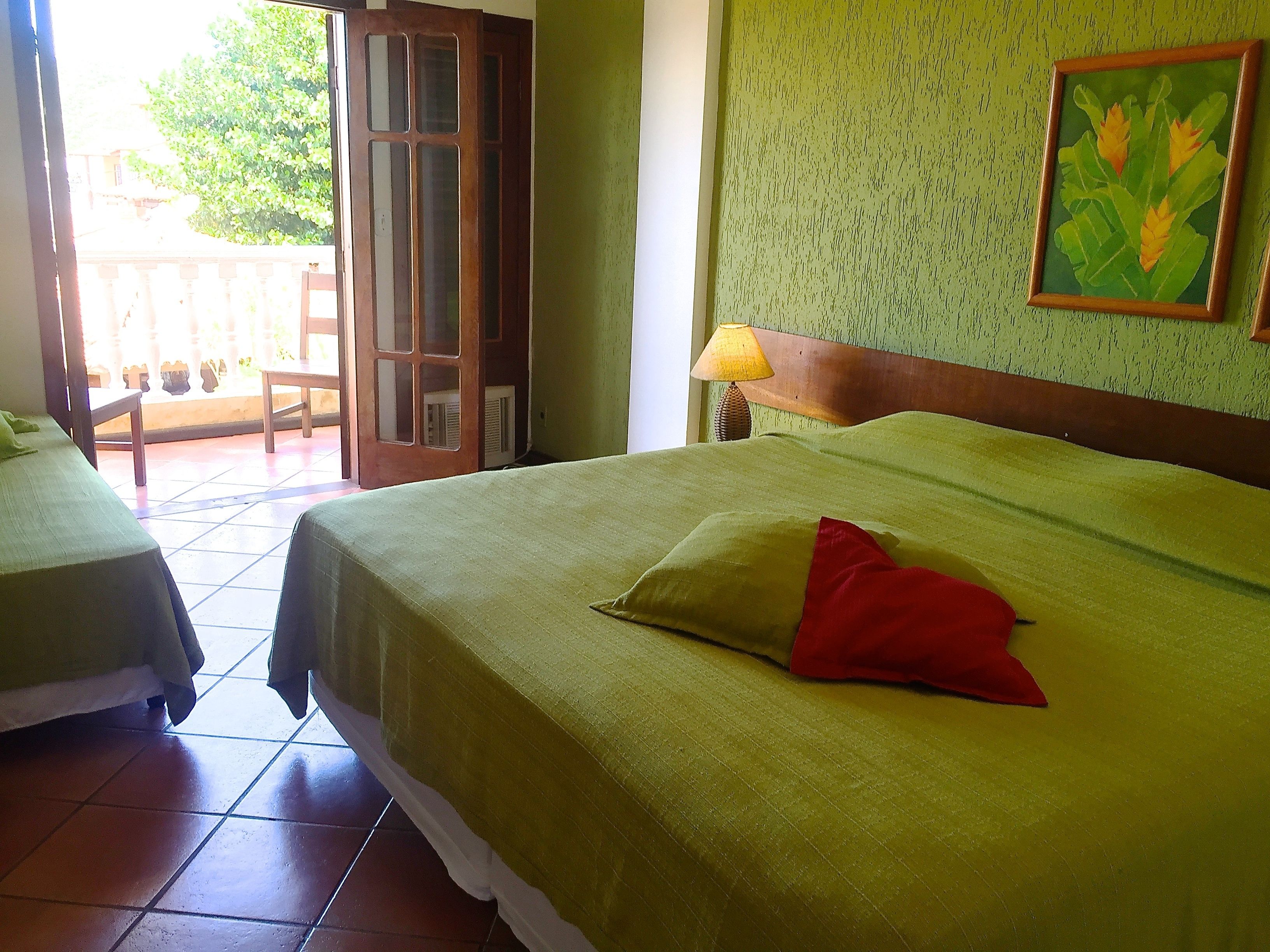A hotel room with two beds, a balcony, and a painting on the wall.