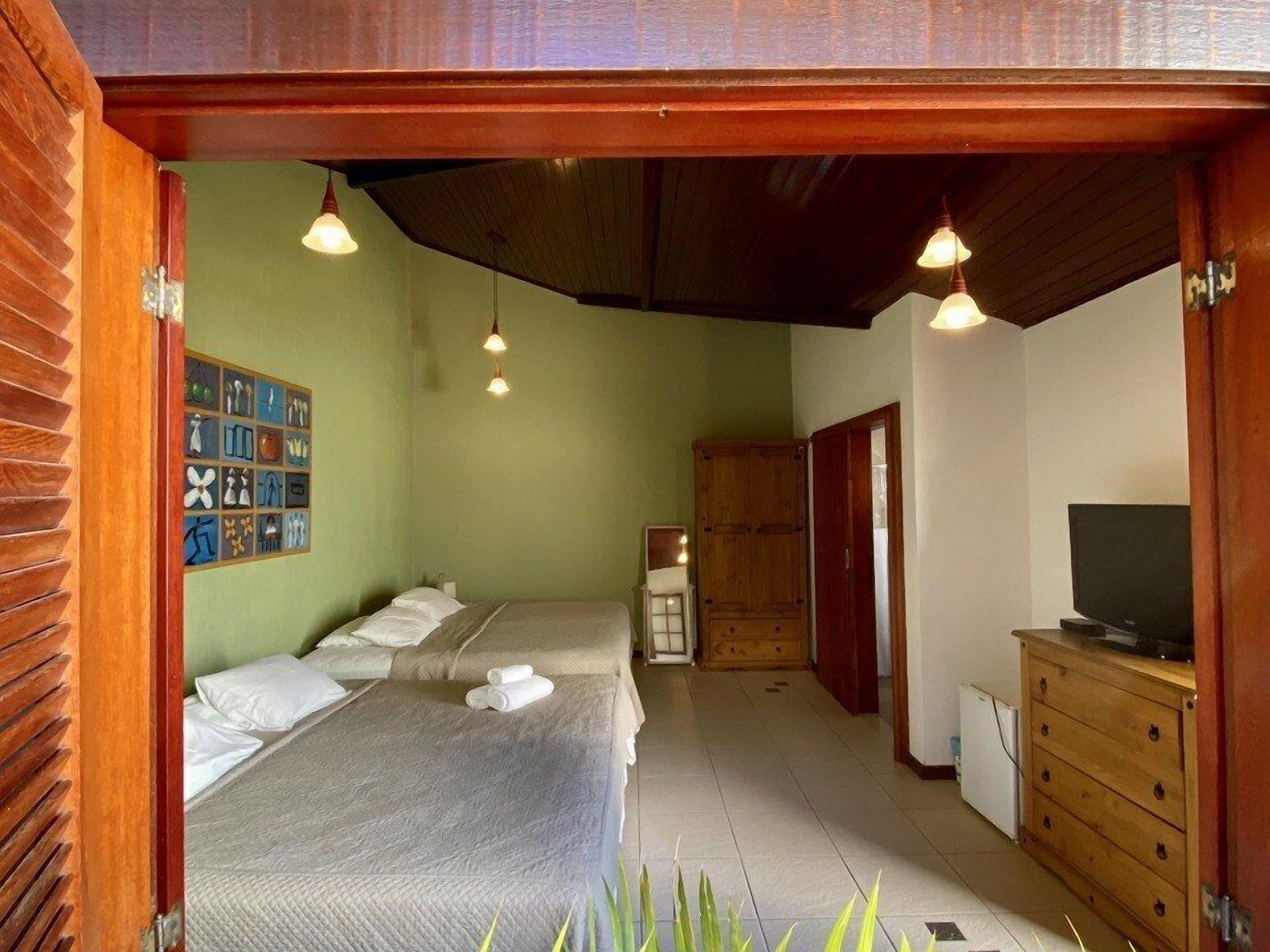 A room with two beds, a television, and a wooden cabinet.