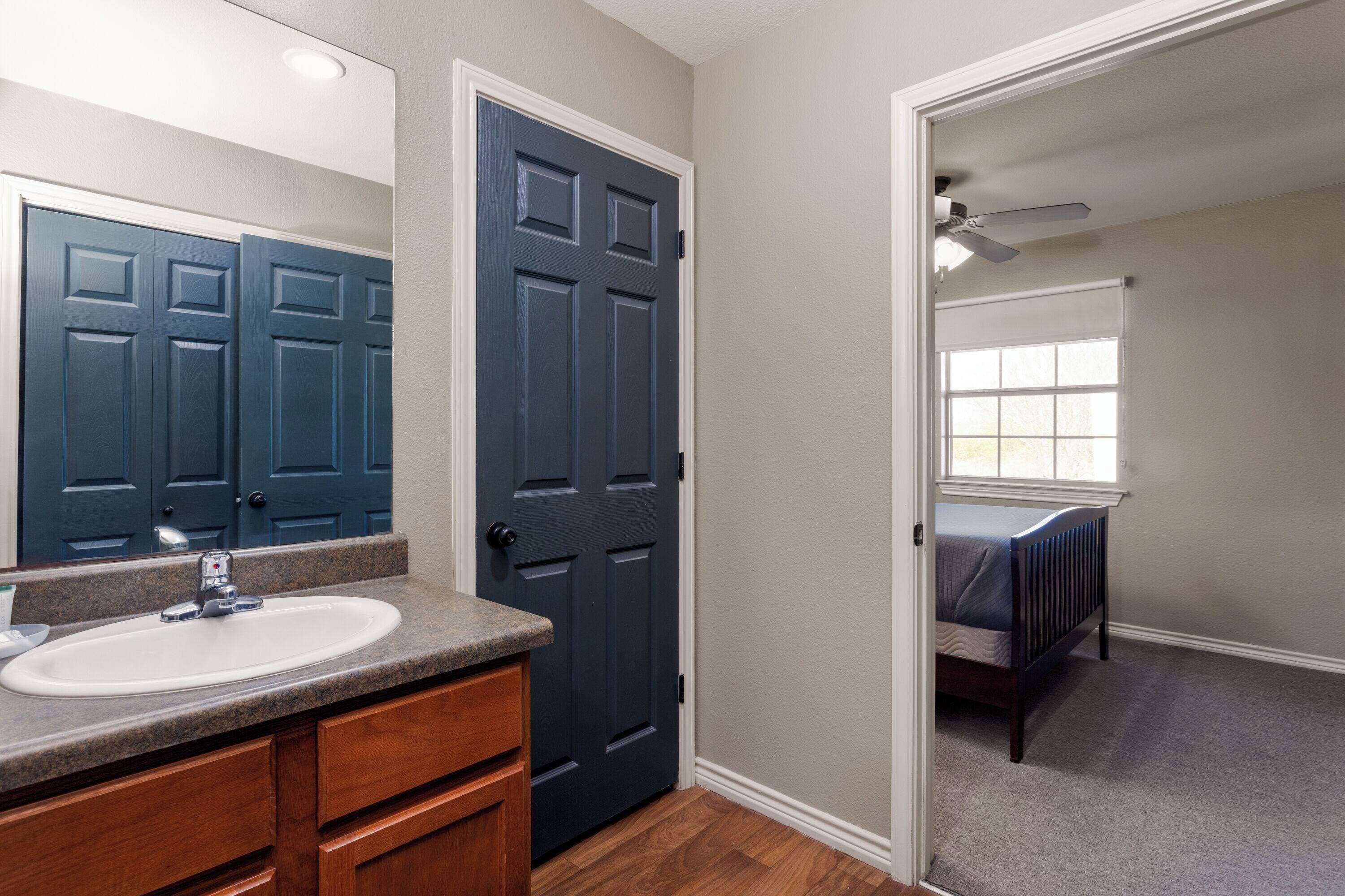 A bathroom with a sink, mirror, and dark blue door.