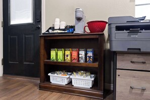 A kitchenette with a coffee maker, tea boxes, and a printer. - Eagle's Den Suites Kenedy a Travelodge by Wyndham (Kenedy)