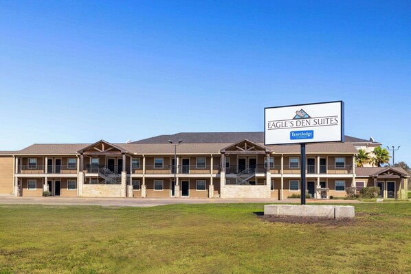 A multi-story building with a sign for Eagle's Den Suites, featuring balconies and a Travelodge logo. - Eagle's Den Suites Kenedy a Travelodge by Wyndham (Kenedy)
