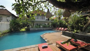 Une terrasse en bois avec des chaises longues et une piscine.
