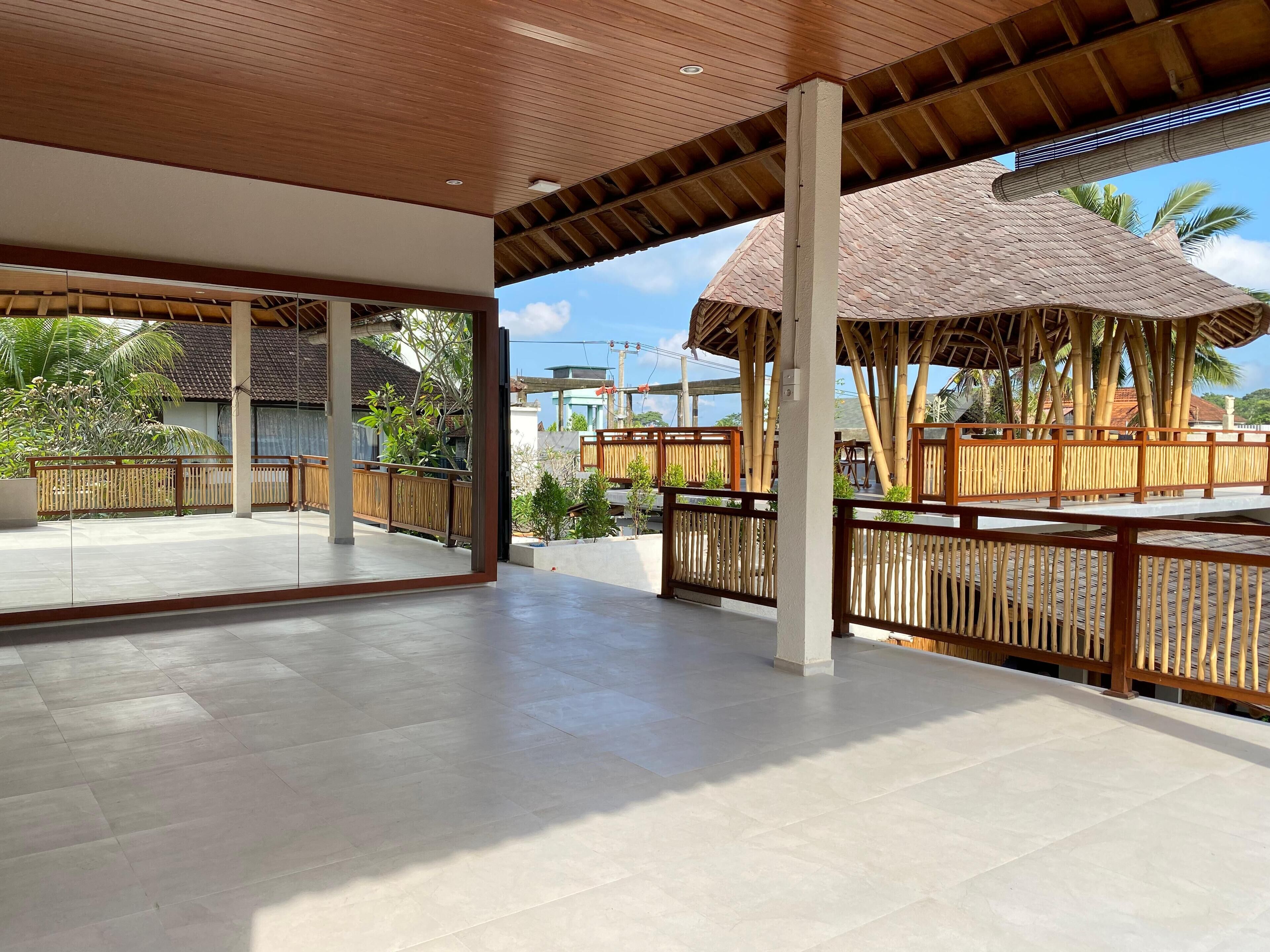 A spacious covered outdoor area with a wooden ceiling and bamboo fence.