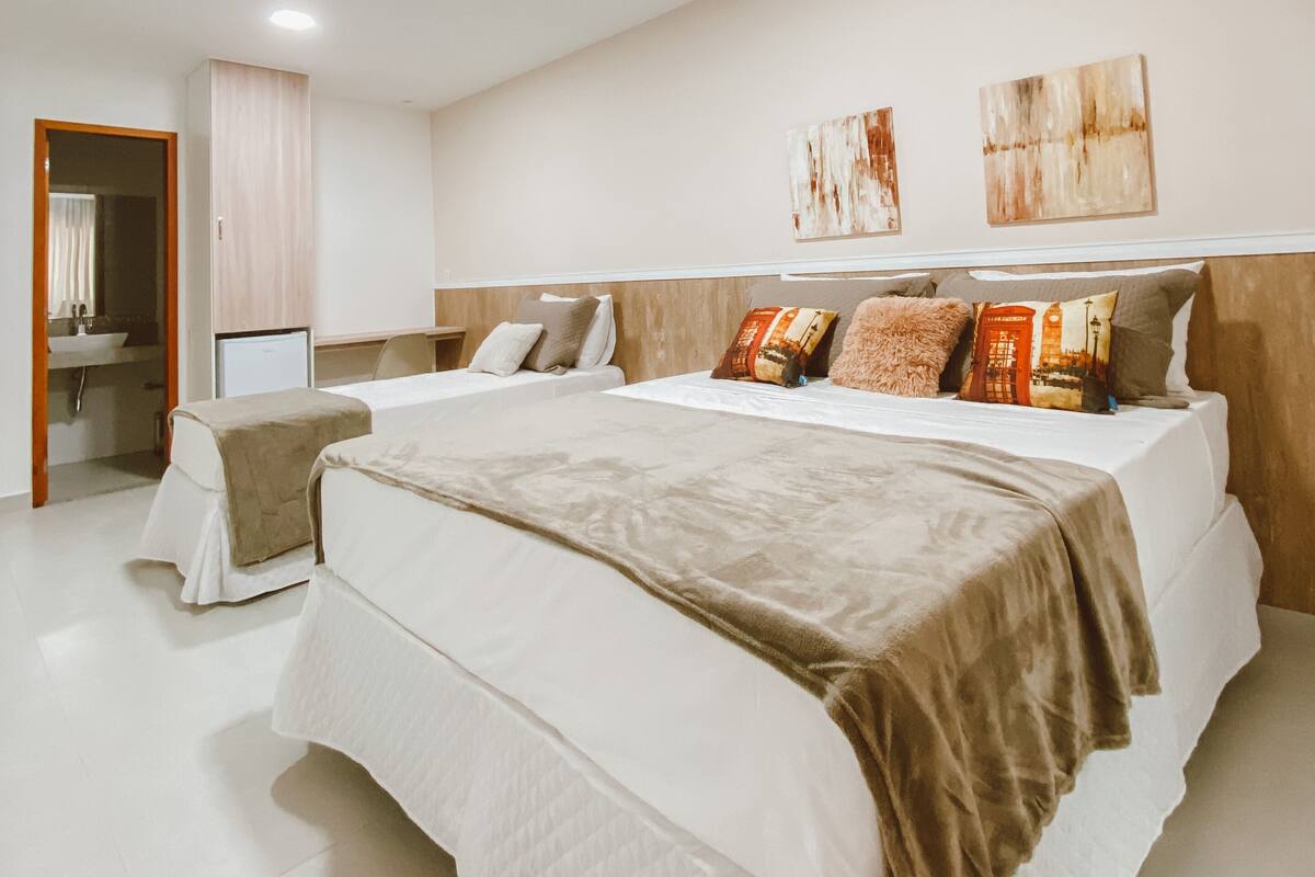 Quarto moderno com uma cama grande, mesas de cabeceira, um espelho e obras de arte na parede.