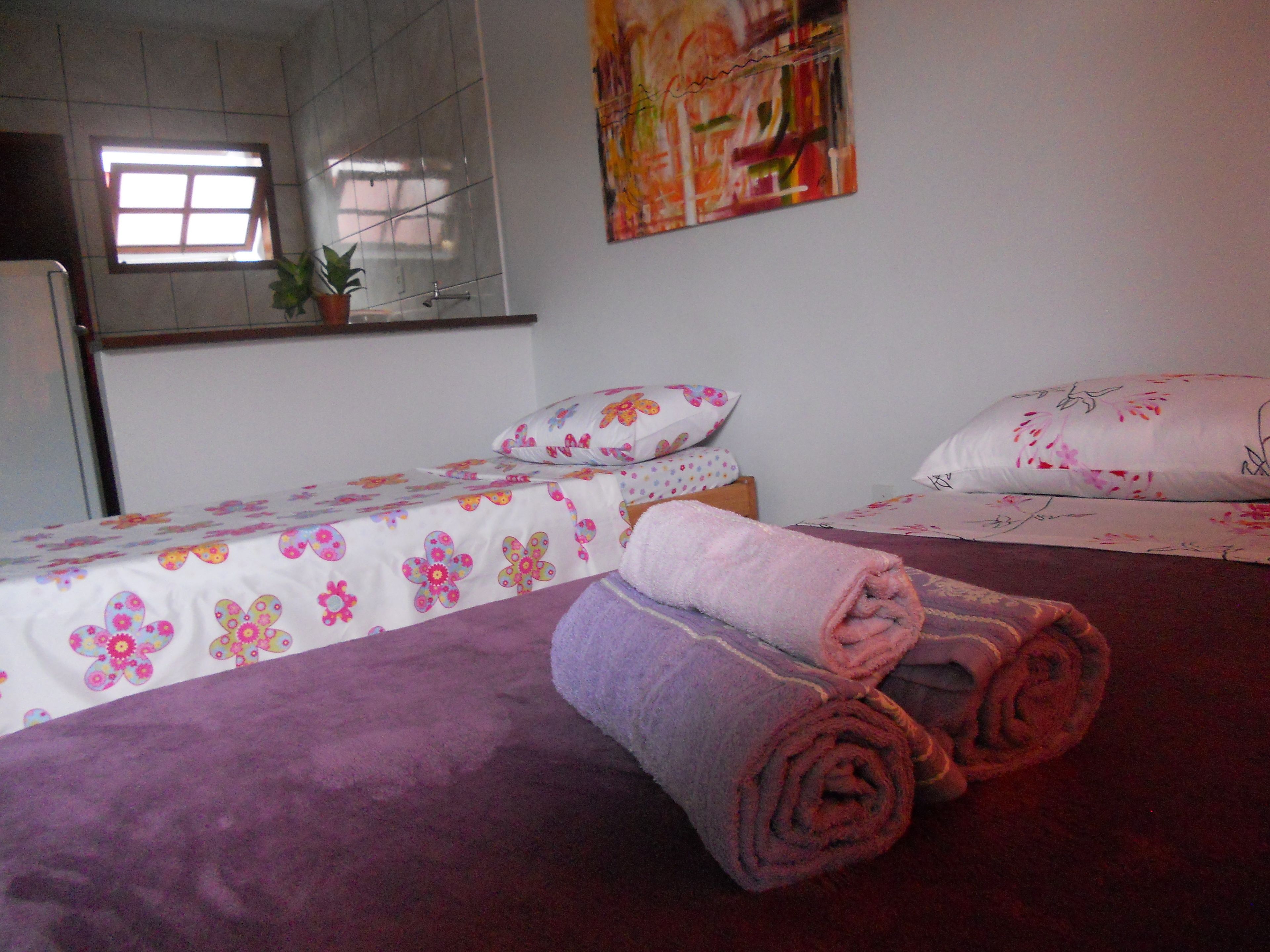 Un dormitorio con dos camas, cada una con ropa de cama floral, una alfombra púrpura y una toalla enrollada en el suelo.