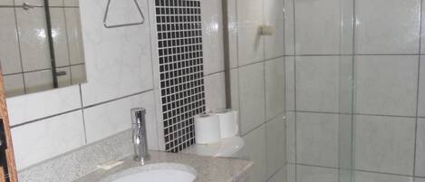 Un baño con lavamanos, inodoro y ducha blancos.