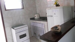 A compact kitchen with a small oven, a washing machine, and a refrigerator. - Pousada Caminho Do Mar (Cabo Frio)