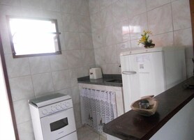 Uma cozinha compacta com forno pequeno, máquina de lavar e frigorífico.