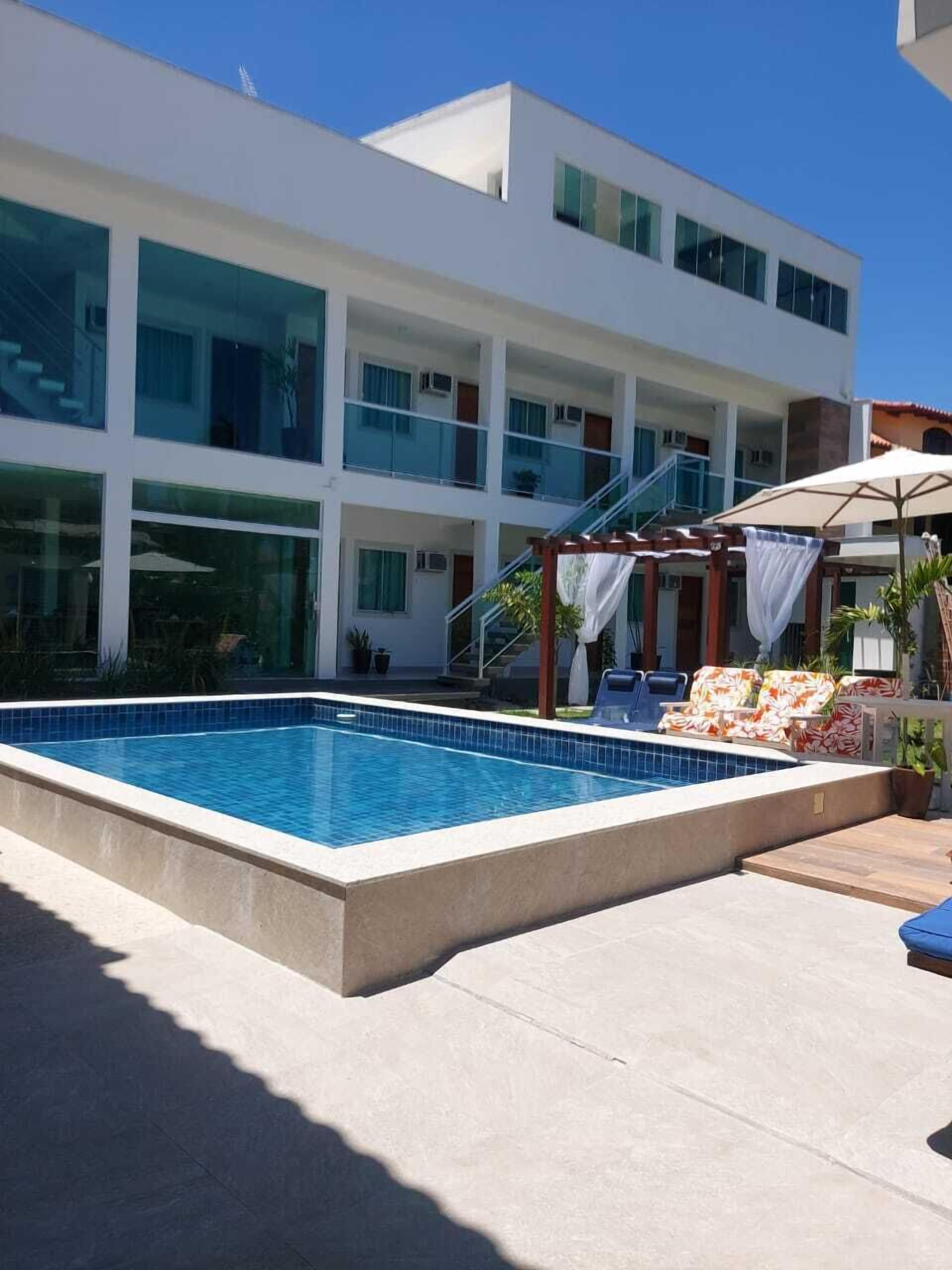 Un hotel moderno con piscina, zona de estar al aire libre y un edificio de varios pisos con balcones.
