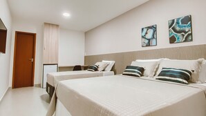 A bedroom with two beds, a desk, and two paintings on the wall. - Pousada Caminho Do Mar (Cabo Frio)