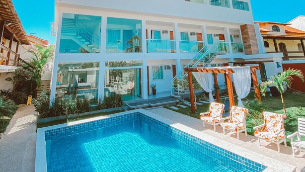 A modern two-story building with a swimming pool in front. - Pousada Caminho Do Mar (Cabo Frio)